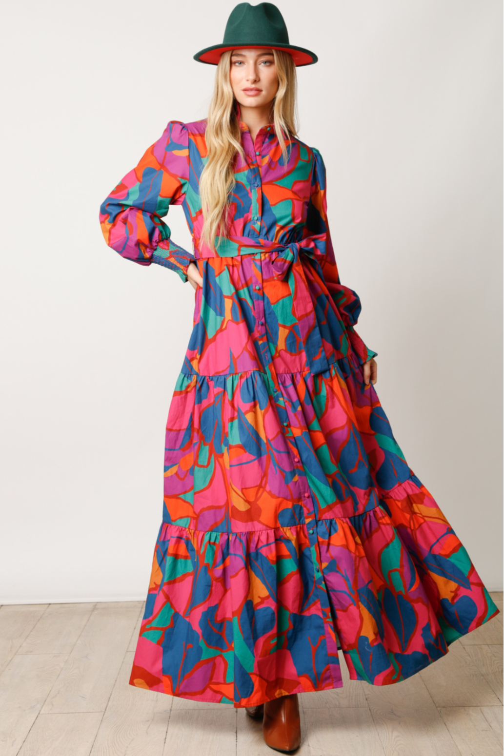 Woman wearing a colorful dress with a pattern, standing against a plain background.